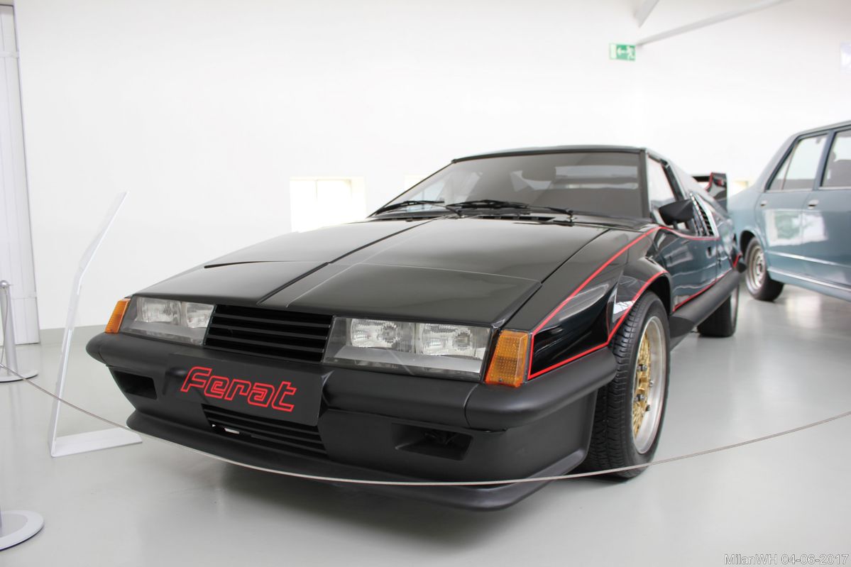 Športové auto čiernej farby s červenými líniami vystavené v múzeu, pohľad spredu v svetlom interiéri.