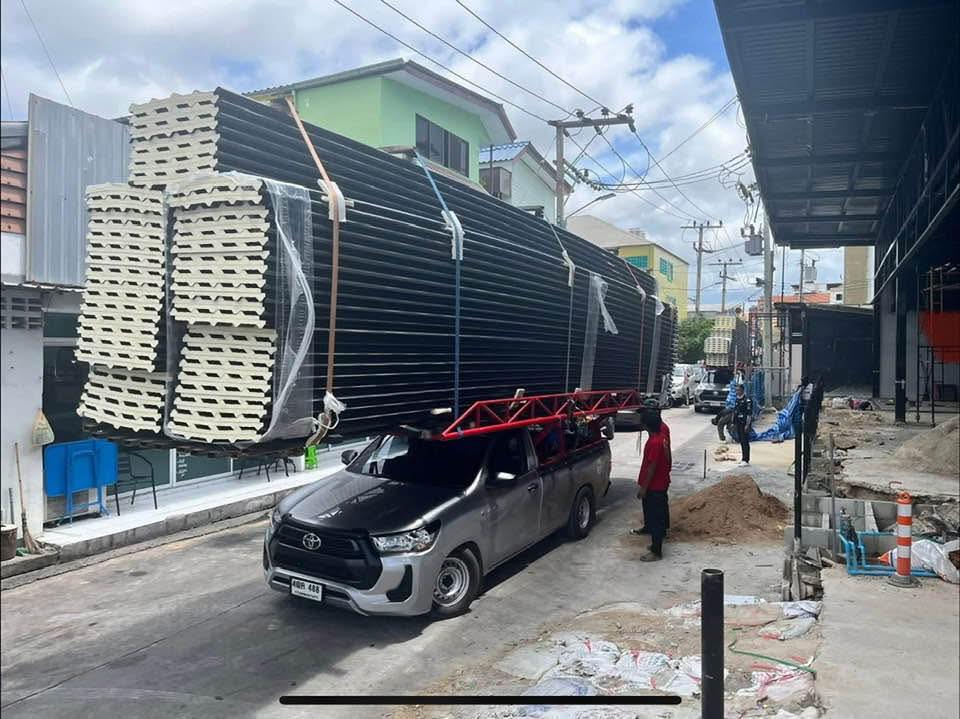 Auto prepravujúce nadmerný náklad na streche na rušnej ulici pri stavebných prácach.