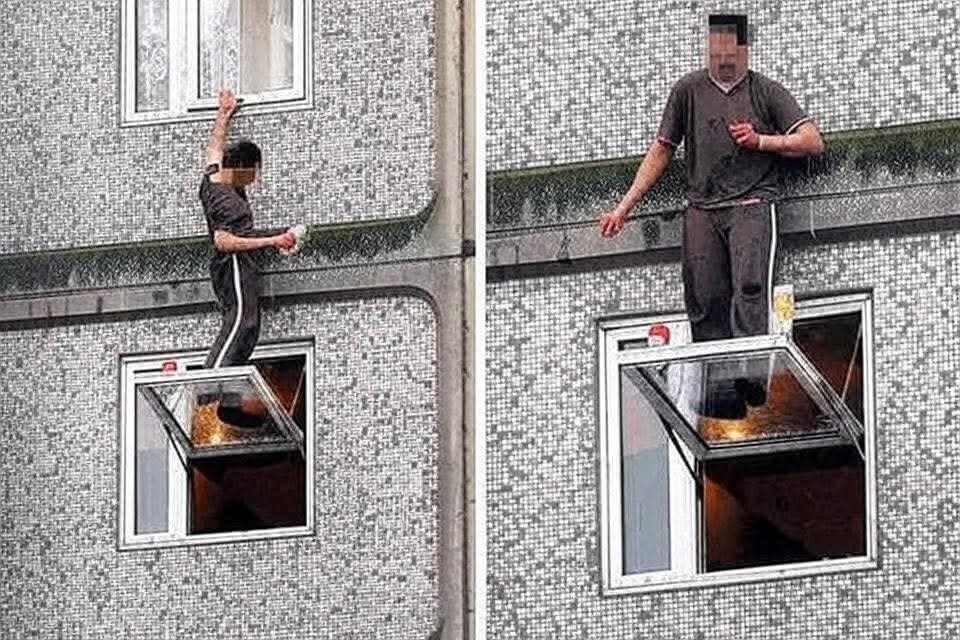 Muž stojí na parapete otvoreného okna, riskantná situácia na budove so šedou mozaikou.