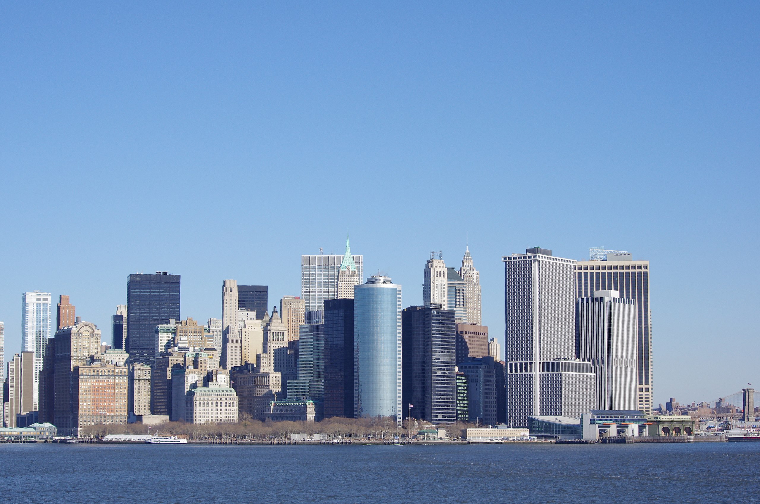 Panoráma mesta s modernými mrakodrapmi a modrou oblohou, pohľad z vody.