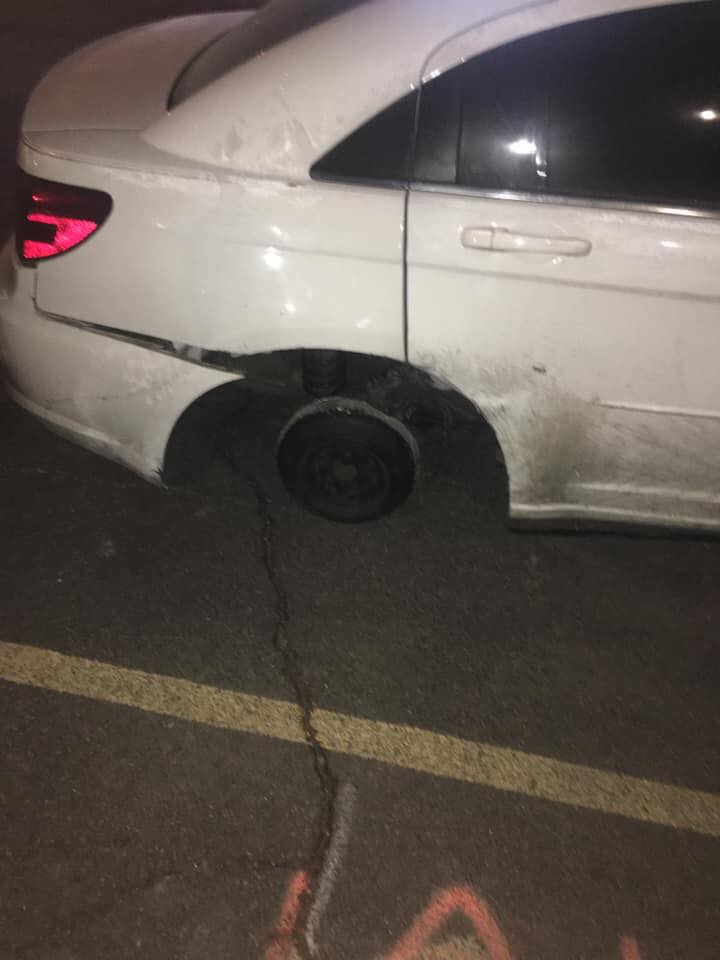 Auto bez zadného kolesa na parkovisku v noci.