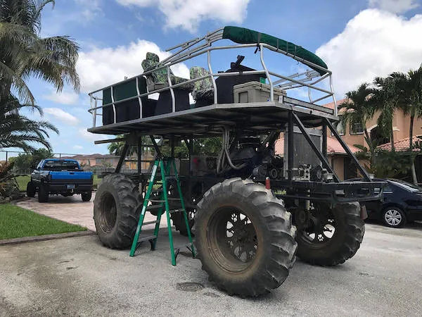 Veľké off-road vozidlo s vyhliadkovou plošinou, zaparkované pred domom na slnečnom dni.