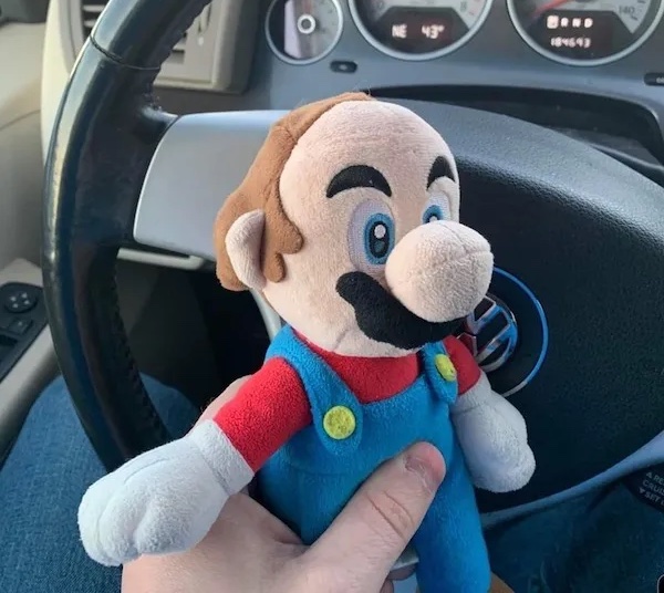 Plyšová postavička v aute pri volante, držiaca v ruke, pripravená na nový výlet.