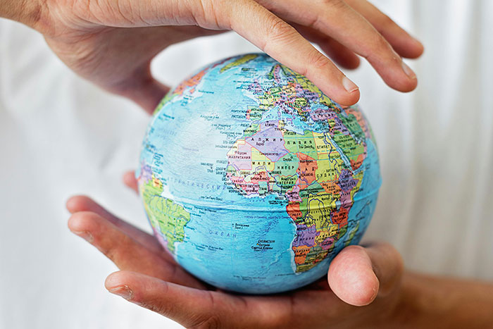 Ruky držiace malý glóbus s mapou sveta, symbolizujúce globálnu starostlivosť a ochranu planéty.