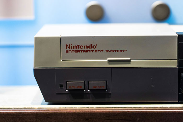 Retro herná konzola Nintendo Entertainment System na modrom pozadí.