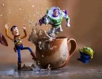 Hračky skáču z hrnčeka, čokoládový nápoj sa rozlieva, vytvárajú dynamický chaos.