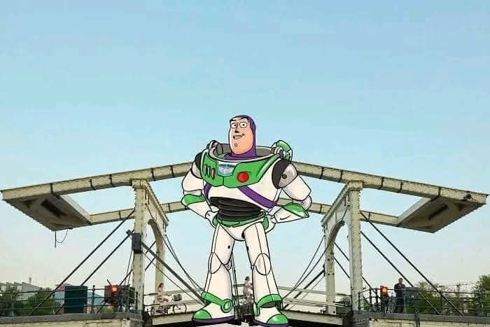 Animovaná postava Buzz Rakeťák stojí na modernej mostnej konštrukcii pod jasnou modrou oblohou.