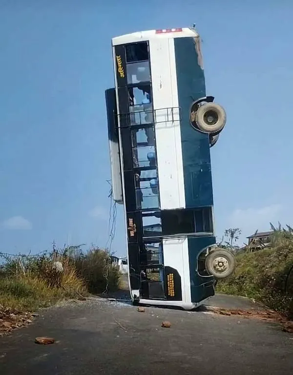 Autobus prevrátený na ceste, stojí na zadnej časti. Neobvyklý dopravný incident.