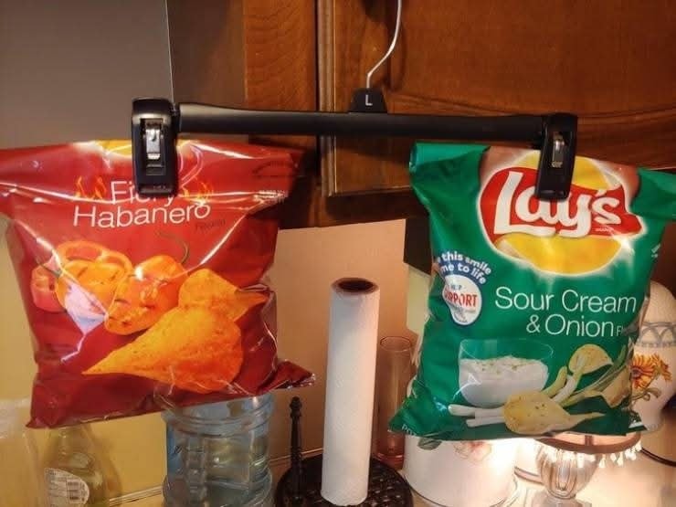 Balenia čipsov zavesené na vešiaku v kuchyni ako kreativne úložné riešenie.