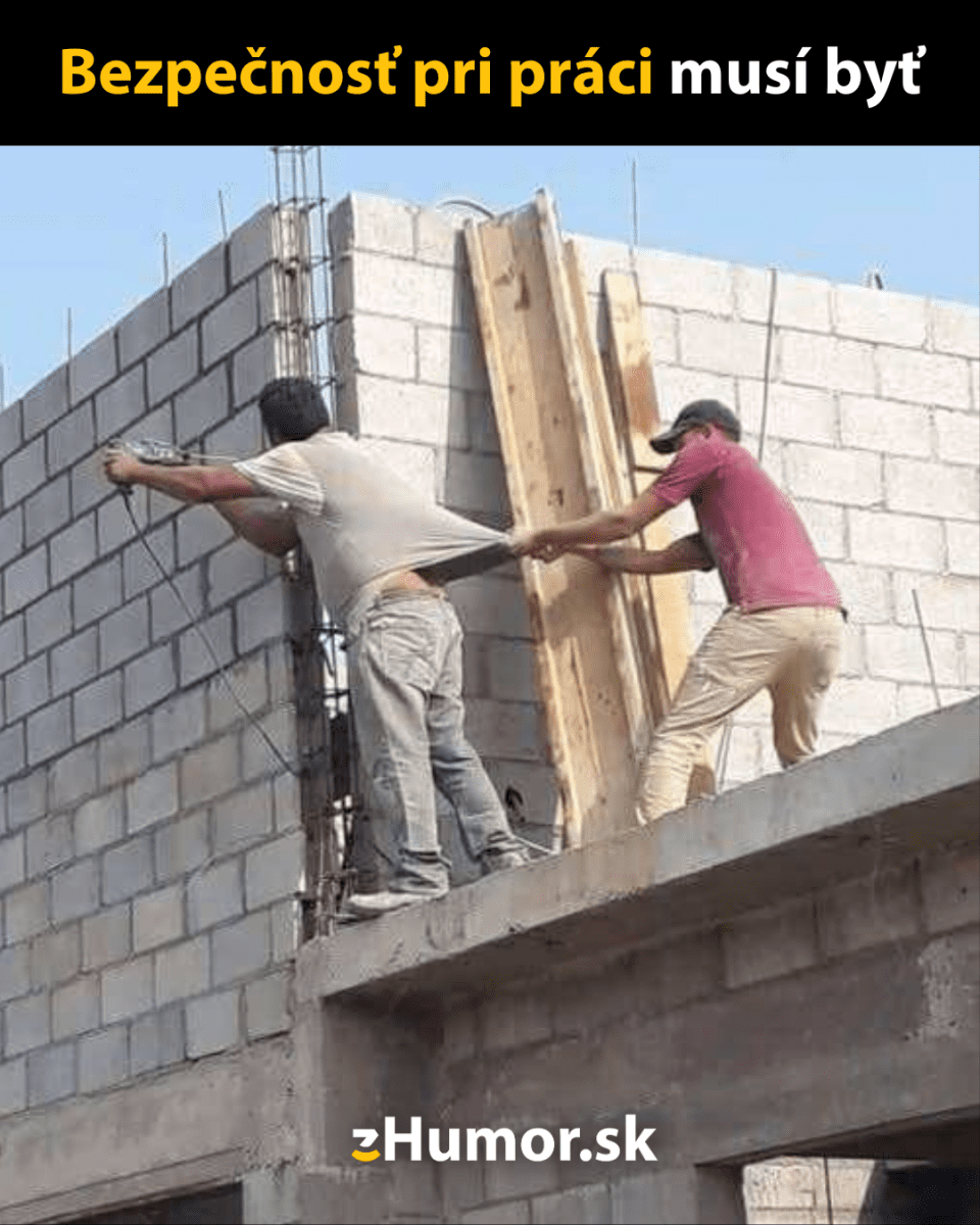 Dvaja robotníci na stavbe, jeden drží druhého za tričko ako improvizovanú formu bezpečnosti pri práci.