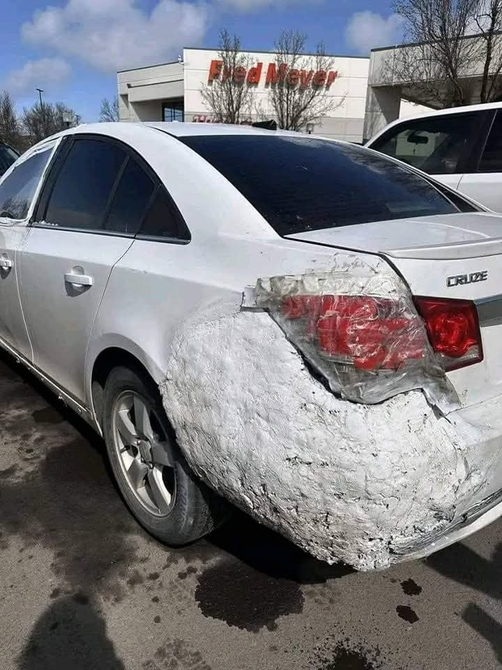 Auto s provizórne opraveným zadným nárazníkom, zaparkované pred nákupným centrom.