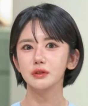 Osoba s krátkymi čiernymi vlasmi a modrým tričkom hľadí priamo pred seba.