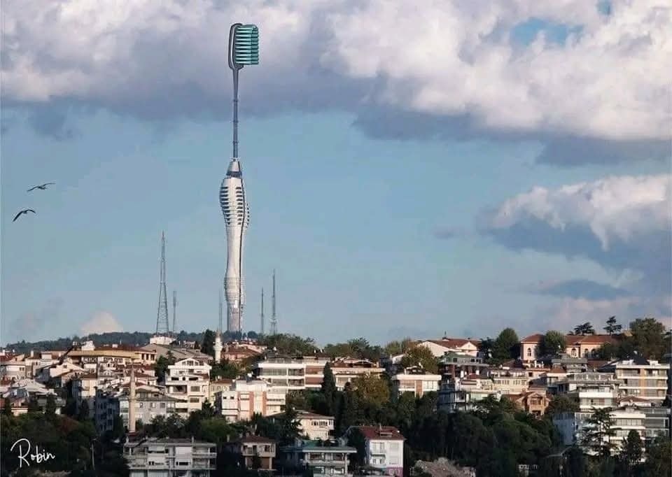 Veža vo forme zubnej kefky nad mestskou panorámou s oblačnou oblohou.