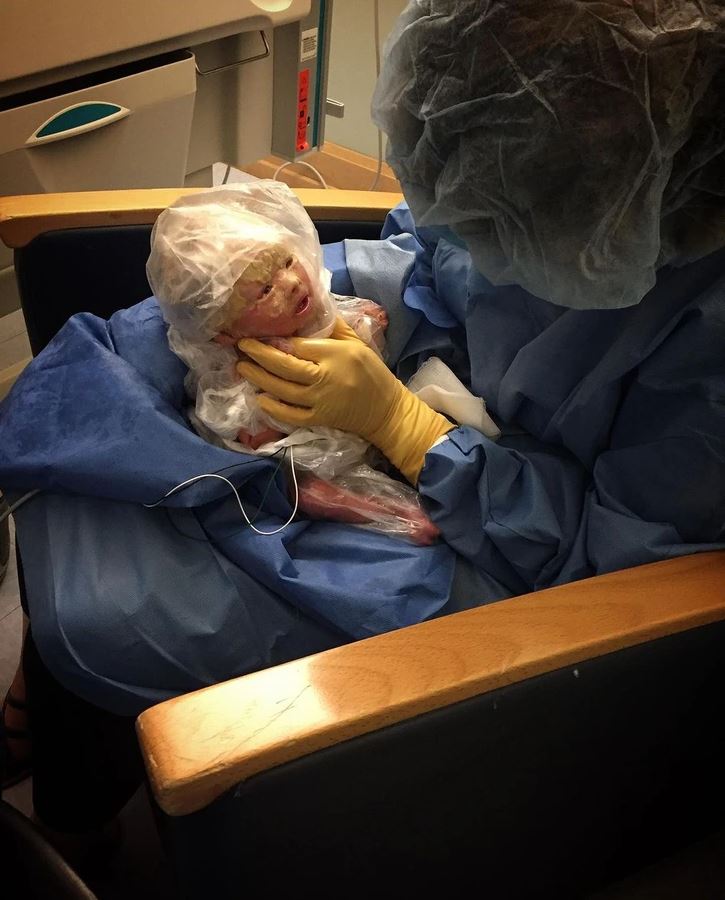 Lekár drží novorodenca v ochrannom obale po narodení, lekárska starostlivosť v nemocnici.