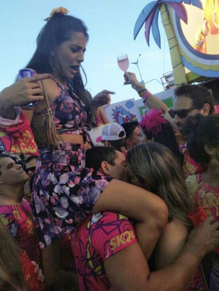 Ľudia sa bavia na preplnenom hudobnom festivale, niektorí s nápojmi v rukách, v atmosfére radosti a zábavy.