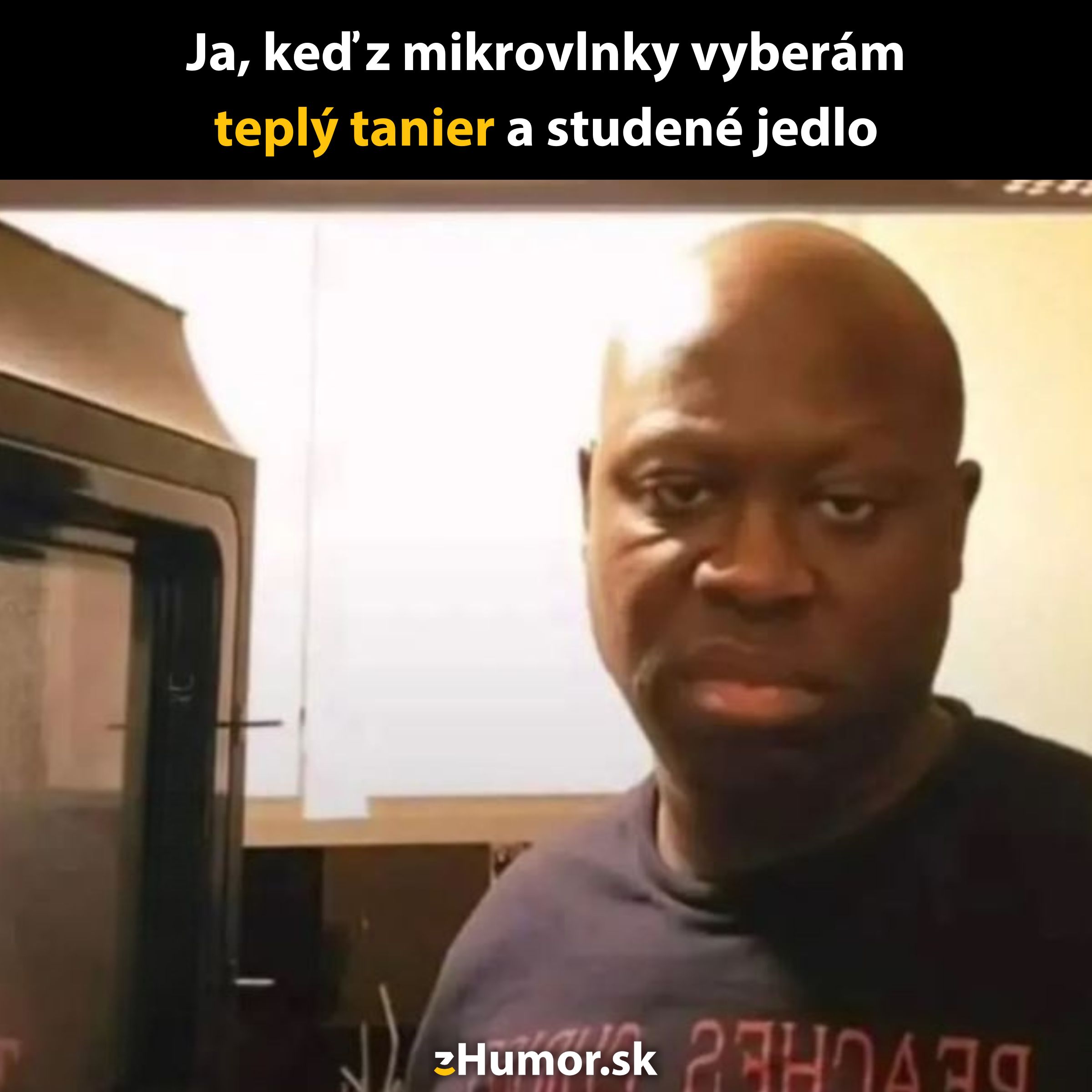 Muž pri mikrovlnke s výrazom frustrácie, teplý tanier a studené jedlo – typická mikrovlnková dilema.