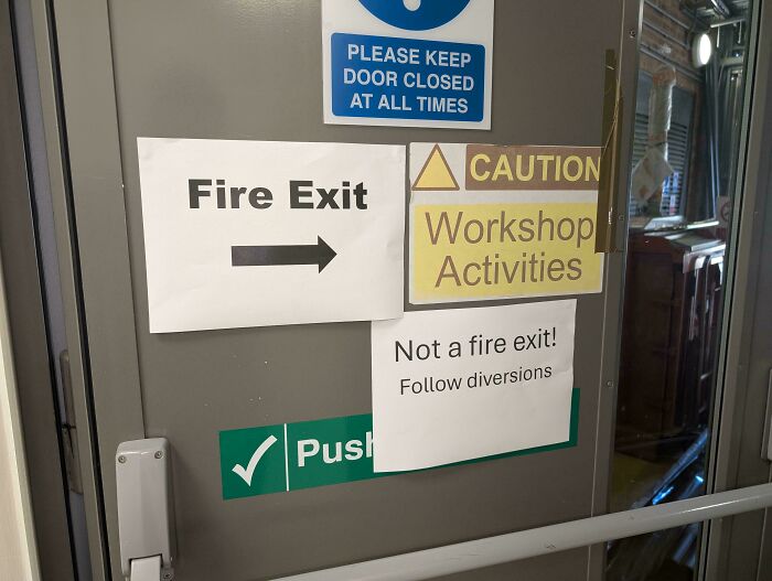 Dvere s protichodnými nápismi: únikový východ a nie je únikový východ. Výstraha na dielňu.