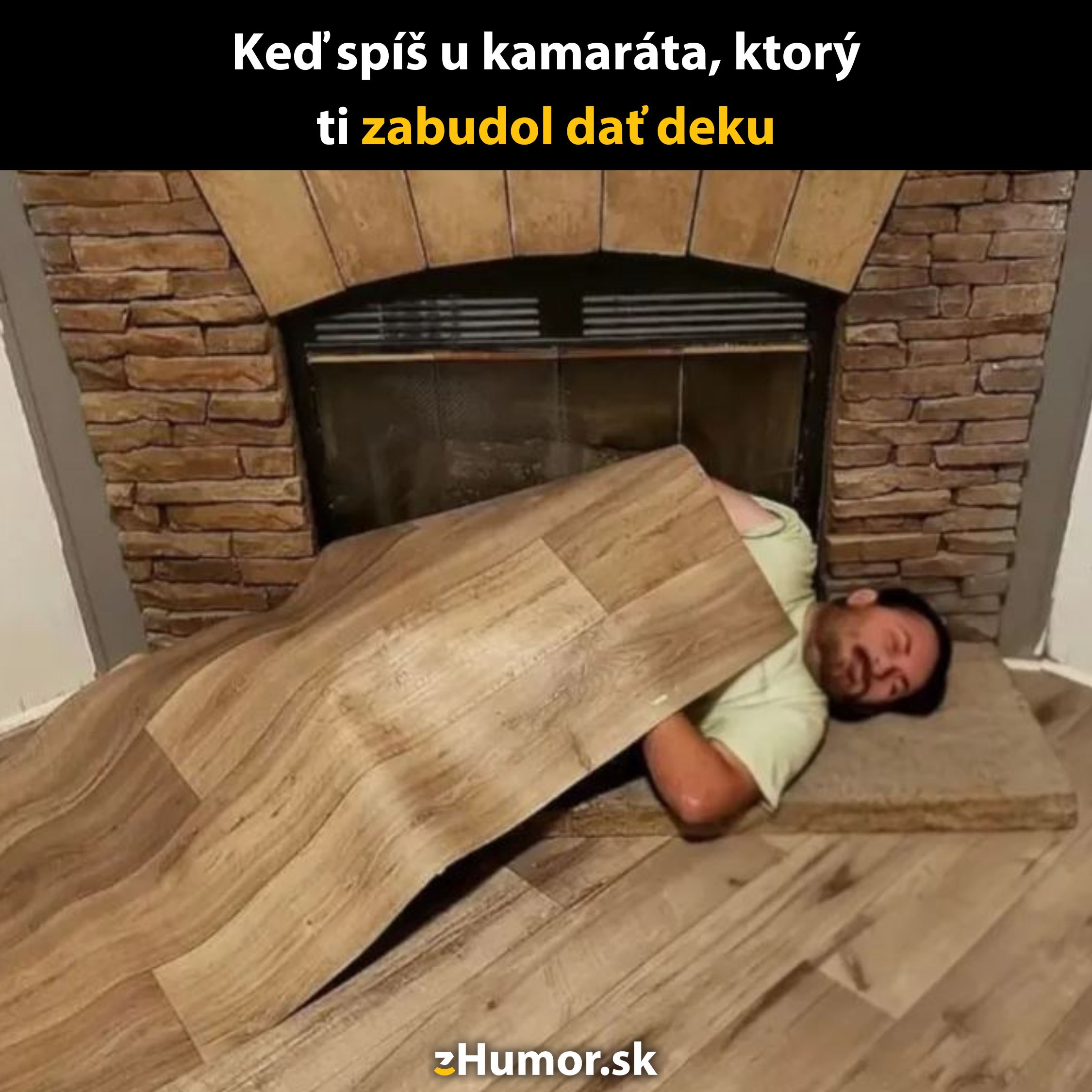 Muž spí na podlahe s laminátom ako prikrývkou pri krbe. Humor o zabudnutej deke u kamaráta.
