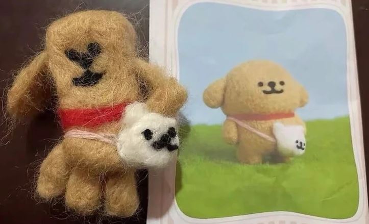 Ručne vyrábaná hnedá plstená postavička psa s bielou taškou vedľa obrázka originálneho dizajnu na modrom a zelenom pozadí.