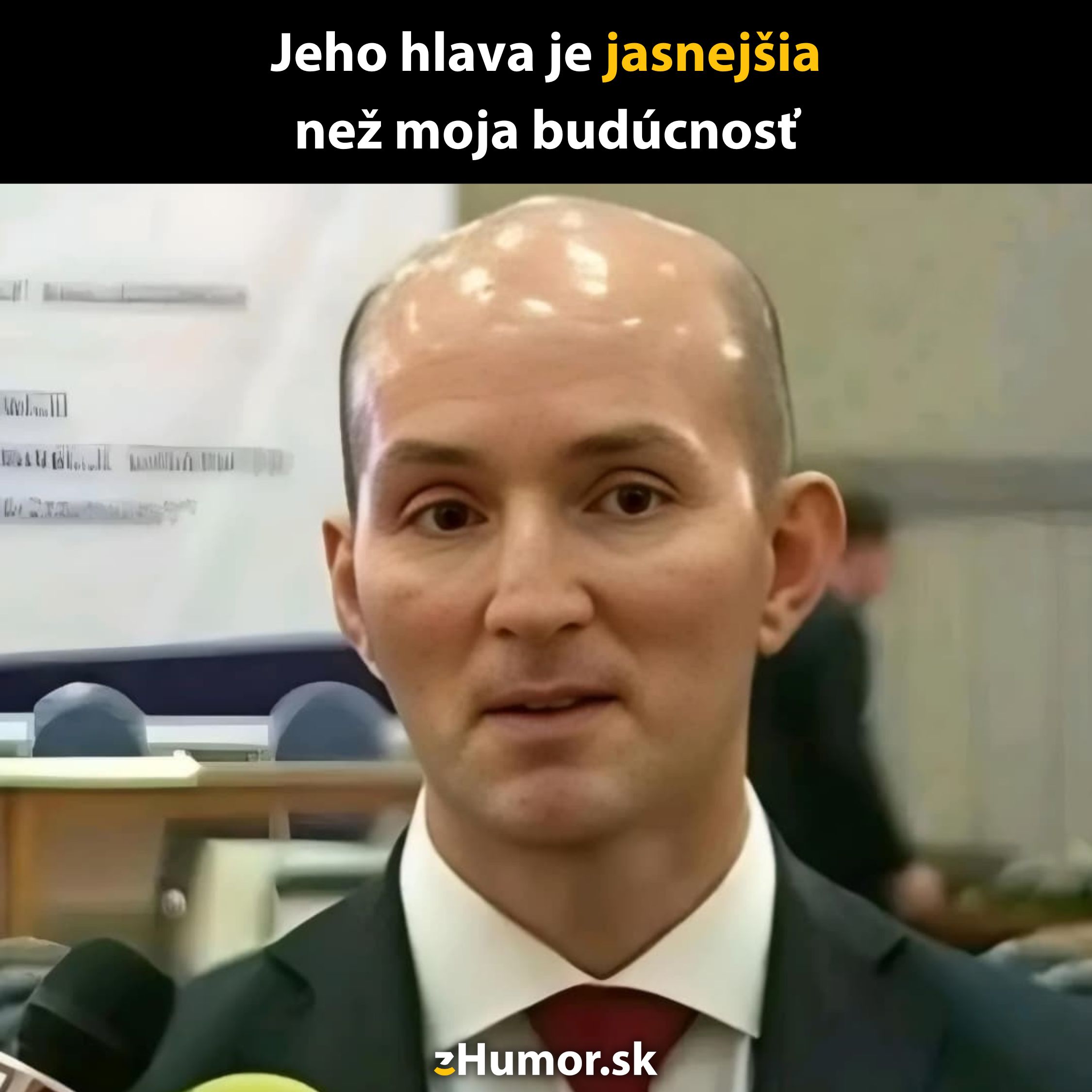 Oholená hlava muža s nápisom: Jeho hlava je jasnejšia než moja budúcnosť. v kancelárskom prostredí.