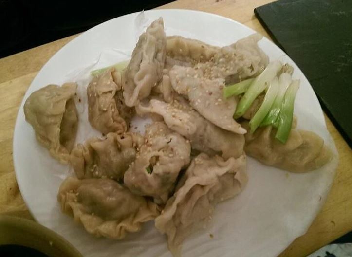 Tanier plný čínskych knedličiek posypaných sezamom a zelenou cibuľkou.