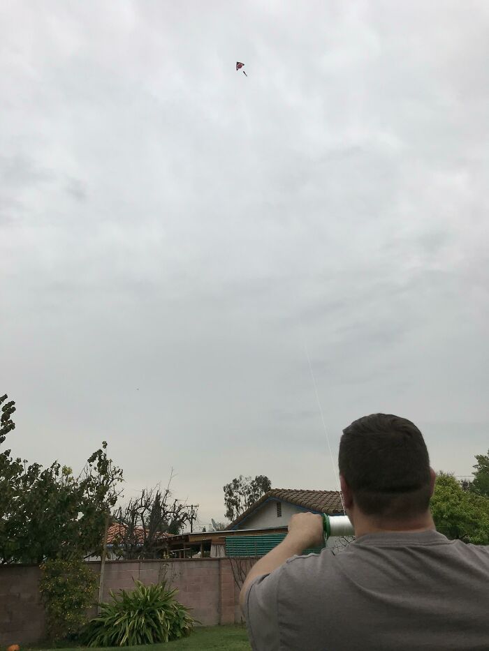 Muž púšťa draka na záhrade pod zamračenou oblohou.