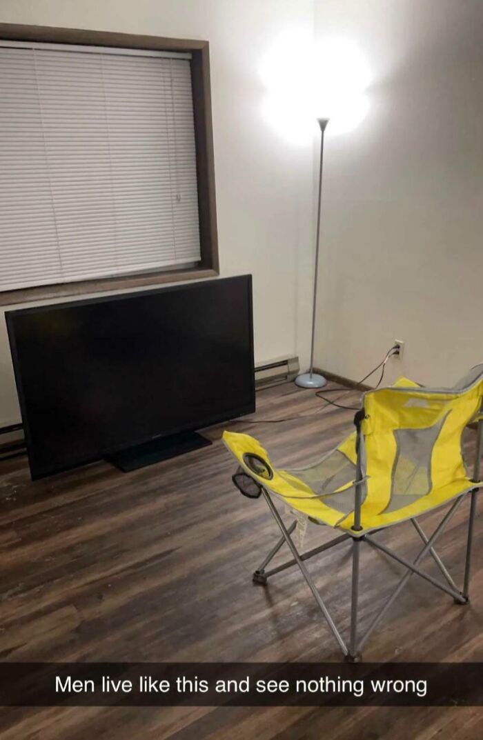 Izba s TV na zemi, žltou skladacou stoličkou a lampou. Minimalistické zariadenie a jednoduchý štýl.