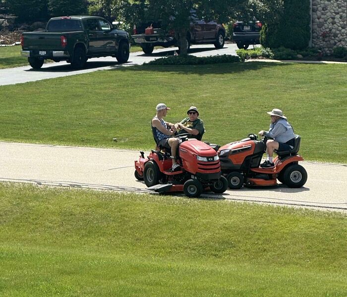 Muži na traktorkách si užívajú slnečný deň na ceste v trávnatej oblasti.