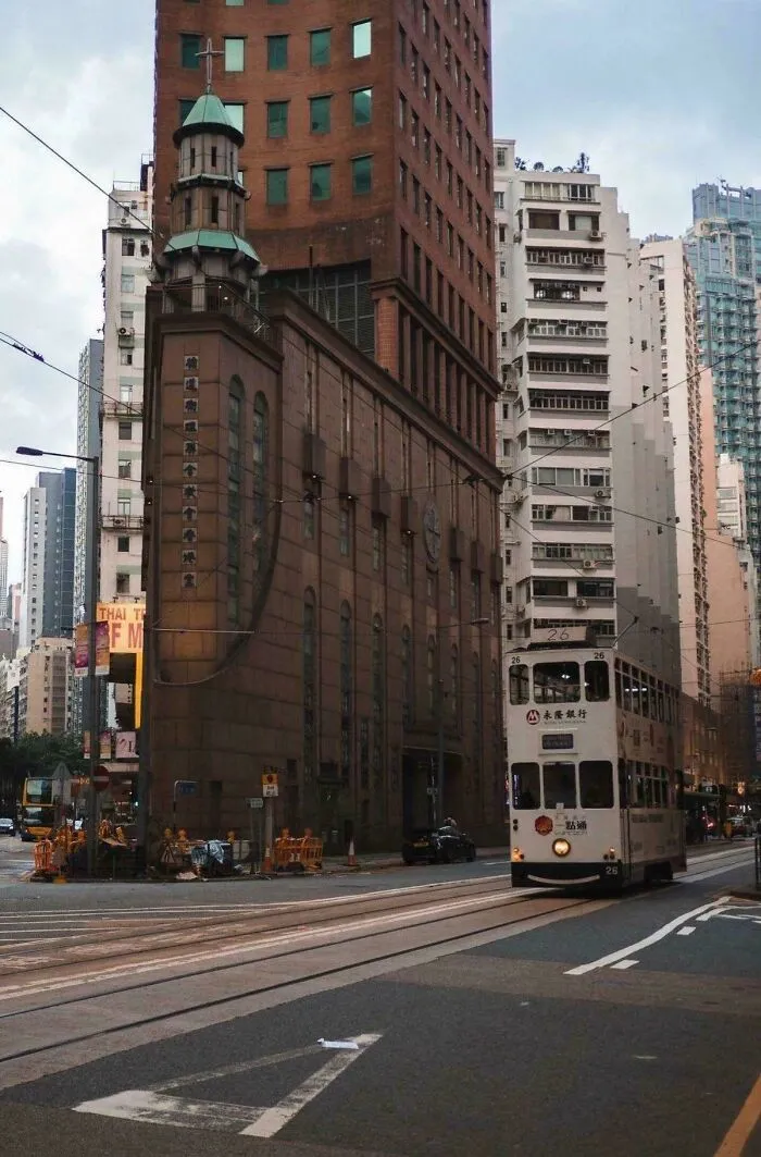 Električka na ulici v Hongkongu, obklopená modernými výškovými budovami, prispieva k mestskej dynamike.