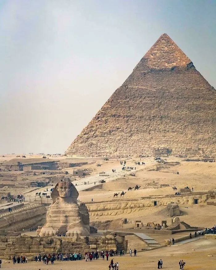 Veľká pyramída v Gíze a Sfinga, ikonické pamiatky starovekého Egypta, púšť a návštevníci v popredí.