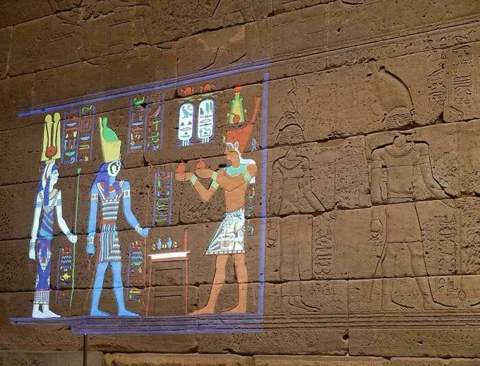 Staroveké egyptské hieroglyfy a rekonštrukcia farebnej maľby bohov na kamennej stene chrámu.