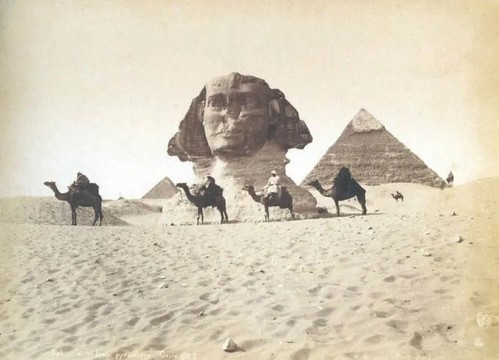 Starodávna Sfinga a pyramídy v Gíze s jazdcami na ťavách, historická fotografia z púšte.