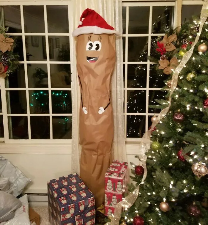 Vianočná dekorácia so zábavným snehuliakom medzi darčekmi a ozdobeným stromčekom v útulnej izbe.