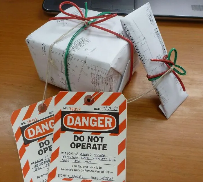 Zabalený balíček so šnúrkami a varovné štítky DO NOT OPERATE na drevenom stole, vedľa laptopu.