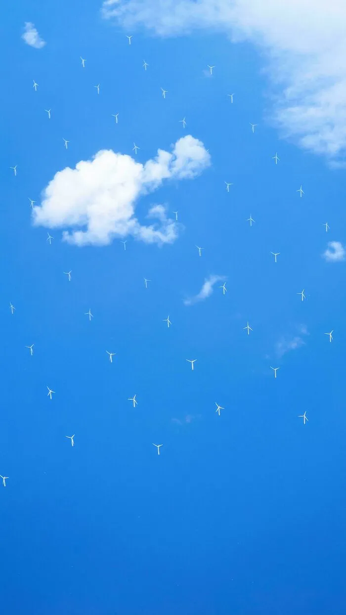 Obloha so vzduchovými turbínami ako oblaky, symbolizujúca obnoviteľnú energiu v modrom pozadí.