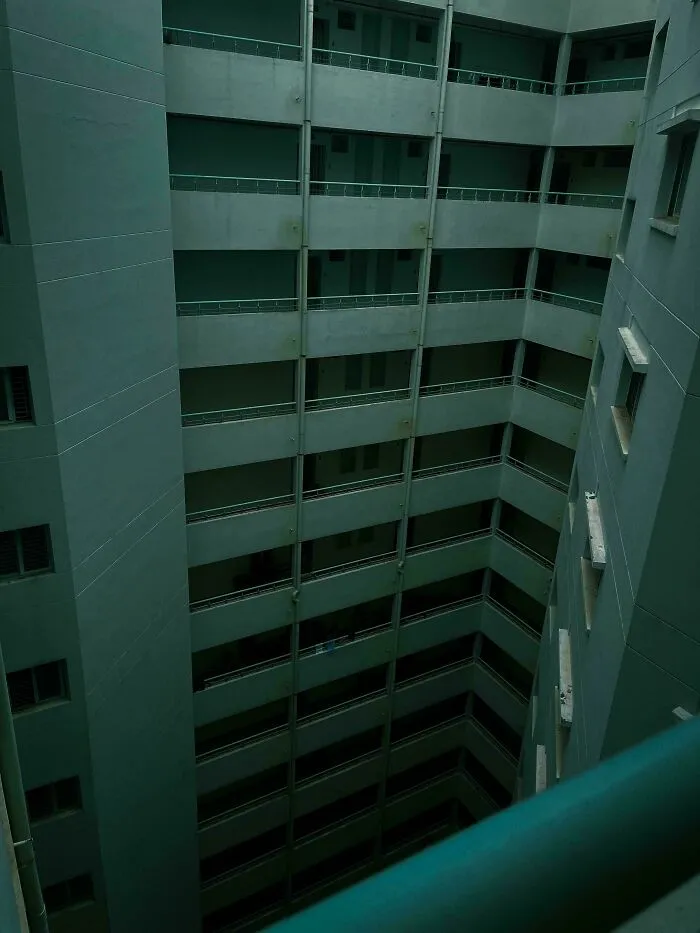 Vnútorný dvor výškovej budovy s viacnásobnými poschodiami a balkónmi, pohľad zhora nadol.