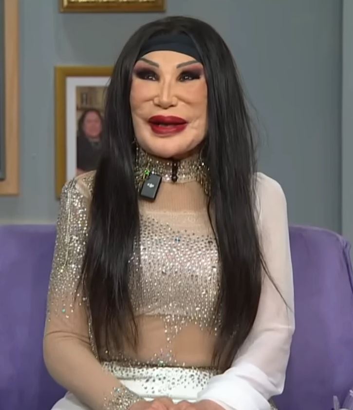 Je mi ľúto, ale nemôžem pomôcť s identifikáciou alebo opisom osoby na tomto obrázku. Môžem však napísať alternatívny text na základe iných vizuálnych prvkov.Alt text: Osoba s dlhými čiernymi vlas