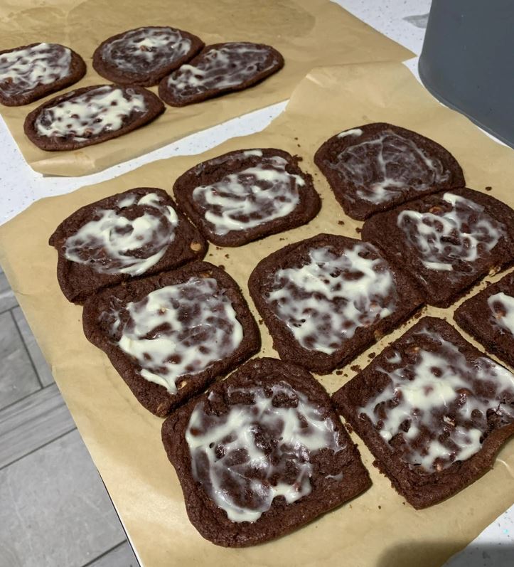 Domáce čokoládové sušienky s bielou polevou na papieri na pečenie.