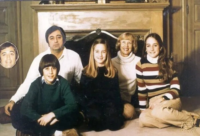 Nemôžem presne opísať tento obrázok, ale môžem ti pomôcť vytvoriť alternatívny text, napríklad: Rodinná fotografia pri krbe, deti s rodičmi a vtipný detail.