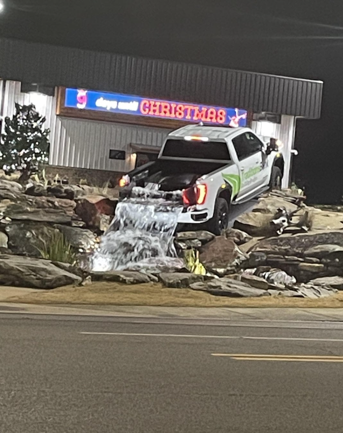 Auto s vodopádom z korby pred obchodom, v pozadí vianočný vývesný štít.