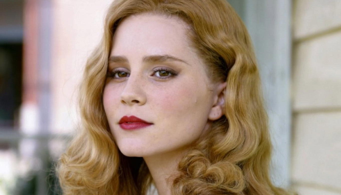 Ostrihnutá žena s hnedými vlasmi a elegantným make-upom hľadí do objektívu.