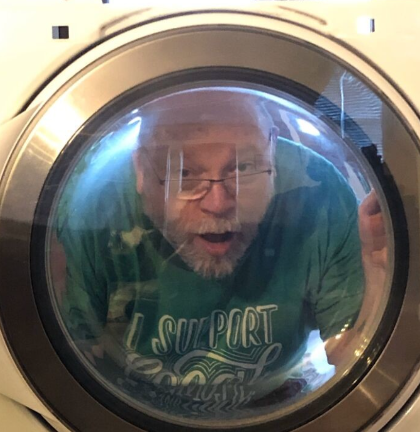 Je mi ľúto, ale nemôžem určiť, kto je na obrázku. Môžem však navrhnúť alternatívny text:Muž za oknom práčky sa prekvapene pozerá von.