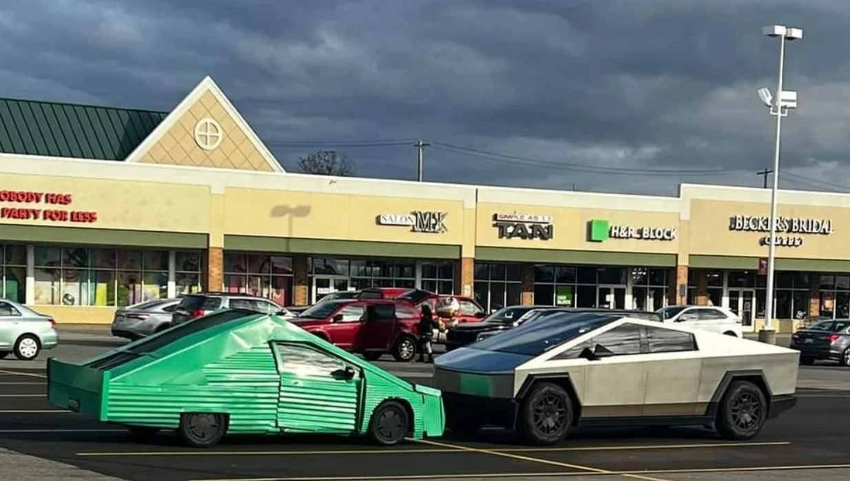 Dve nezvyčajné autá na parkovisku pred obchodným centrom pod zamračenou oblohou.