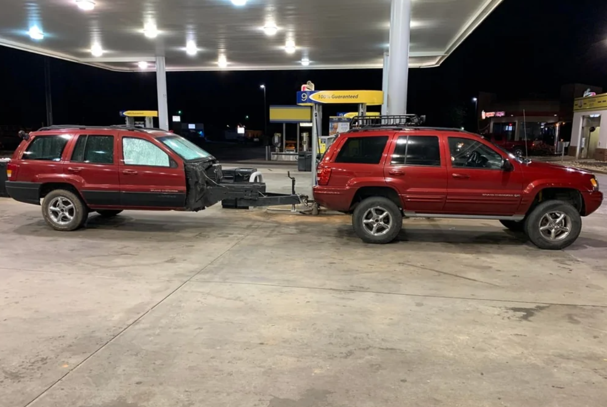 Dve červené SUV spojené na benzínovej pumpě, s originálnym riešením prívesu.