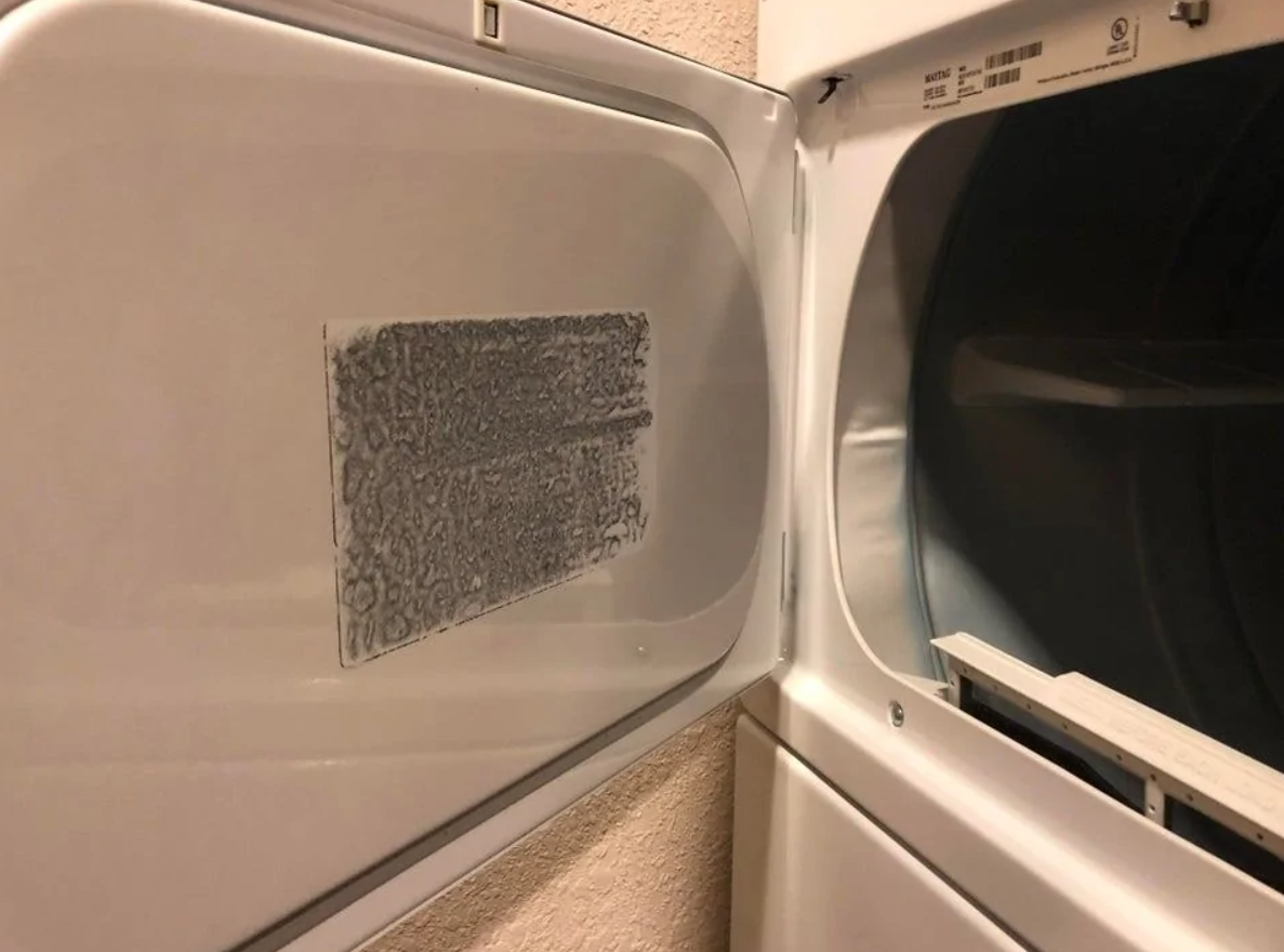 Sušička s otvorenými dvierkami, zboku viditeľný filtračný systém na zachytenie vlákien.