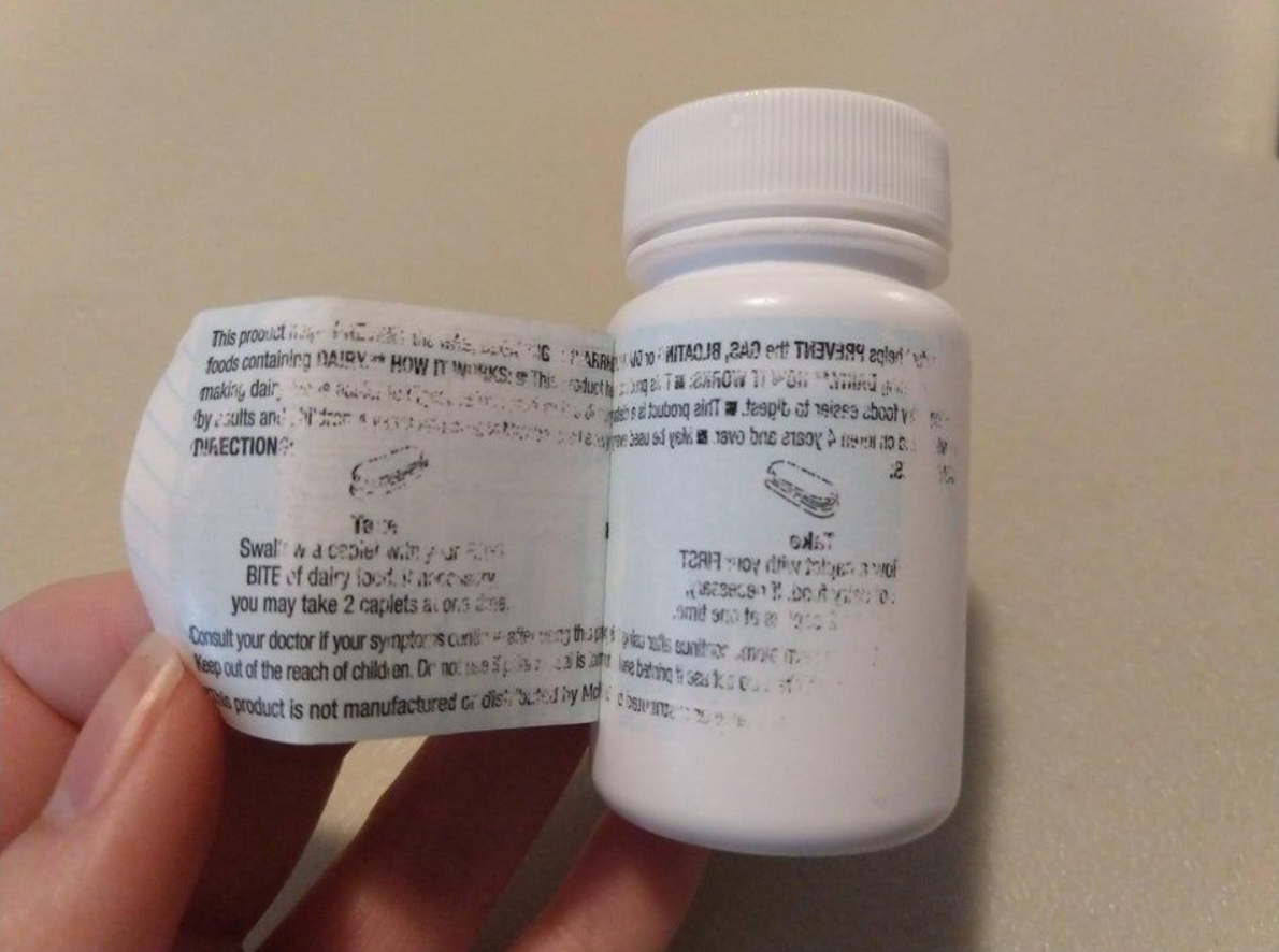 Plastová fľaštička s rozbalenou etiketou lieku. Viditeľná drobná potlač textu na etikete.