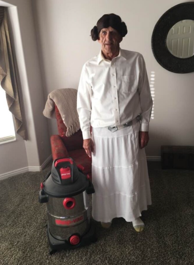 Osoba oblečená ako princezná Leia s vysávačom v obývačke. Kreatívny kostým na domáce použitie.