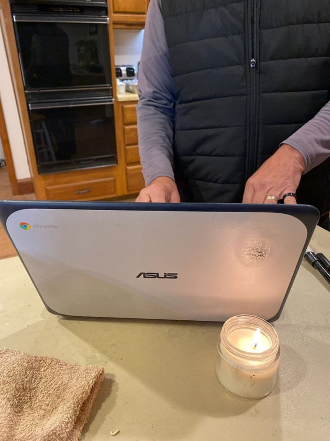 Osoba píše na notebooku ASUS pri sviečke v kuchyni, na stole uterák a fixka.