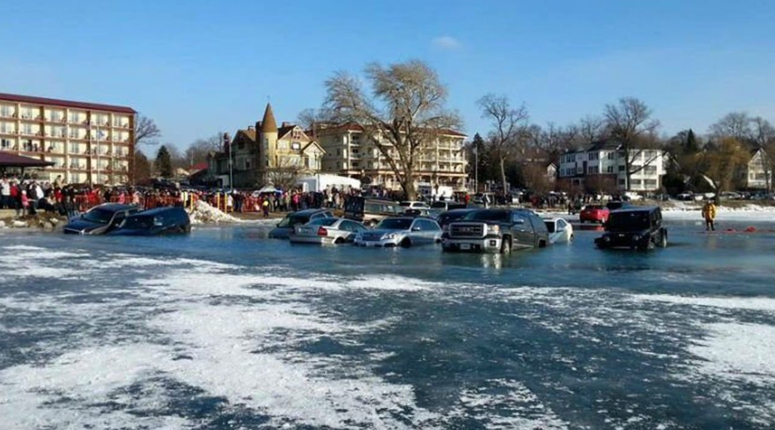 Autá prepadnuté cez ľad na zamrznutom jazere, s divákmi na brehu.