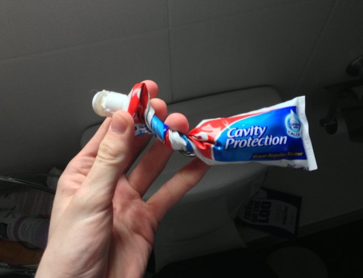 Ruka držiaca zrolovanú tubu zubnej pasty na ochranu pred zubným kazom v kúpeľni.